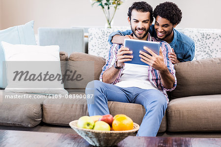 Happy gay couple using tablet