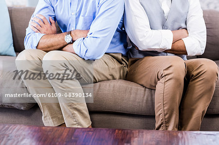 Gay couple sitting back-to-back after arguing