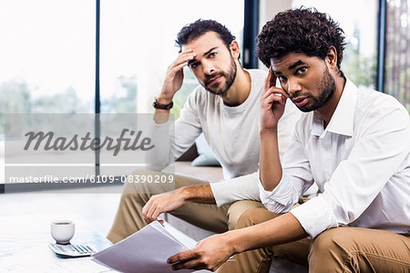 Gay couple paying bills and looking at camera