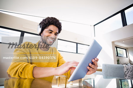 Smiling man using tablet and headphones