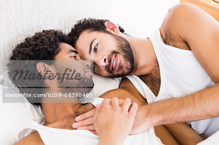 Happy gay couple laying on bed