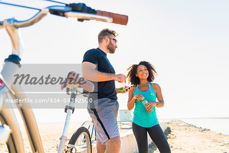 Couple taking a break from cycling, holding bottle drink
