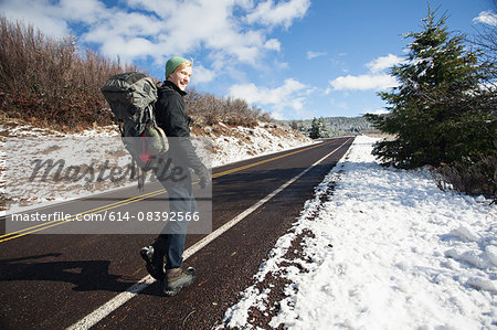 Young male hiker hiking on rural road in snow covered landscape, Ashland, Oregon, USA