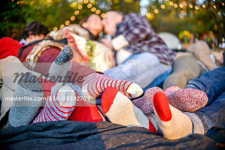 Entwined family socked feet lying on blanket in woods