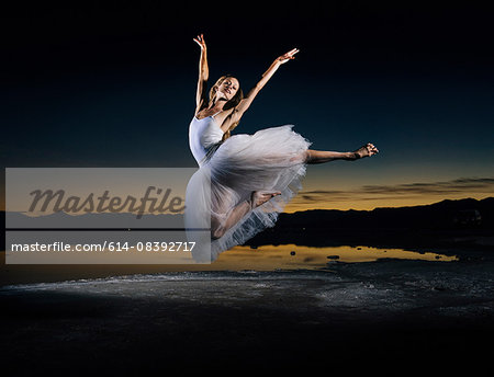Young female ballet dancer leaping over Bonneville Salt Flats at sunset, Utah, USA