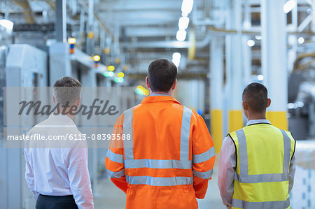 Workers and supervisor standing in factory corridor