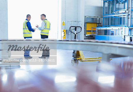 Workers in reflective clothing talking at warehouse loading dock doorway