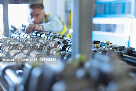 Engineer examining printing press conveyor belt Engineer examining printing press conveyor belt