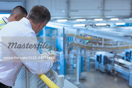 Workers leaning on railing overlooking factory
