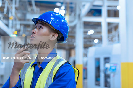 Worker in hard-hat using walkie-talkie in factory