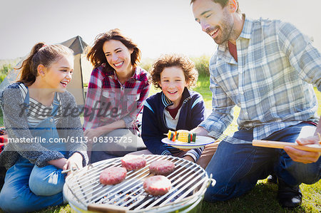 Family barbecuing at sunny campsite