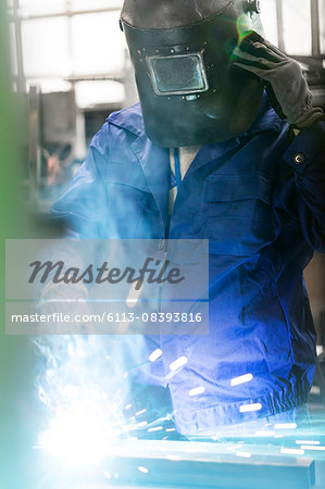 Welder in protective workwear working in factory