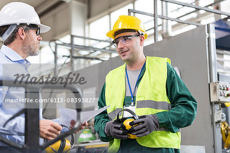 Engineer and worker in protective workwear talking in factory