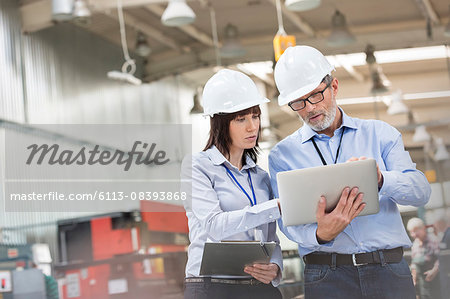 Engineers with laptop in factory