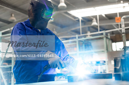 Welder in protective workwear using welding torch in steel factory Welder in protective workwear using welding torch in steel factory