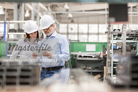 Engineers using digital tablet in steel factory