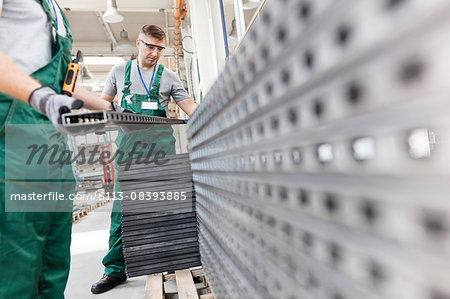 Workers lifting steel parts in factory