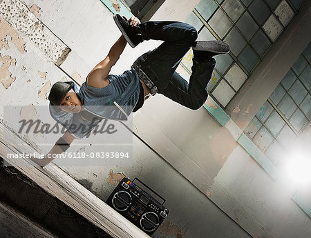 A young man breakdancing on the street of a city, doing a one handed handstand.