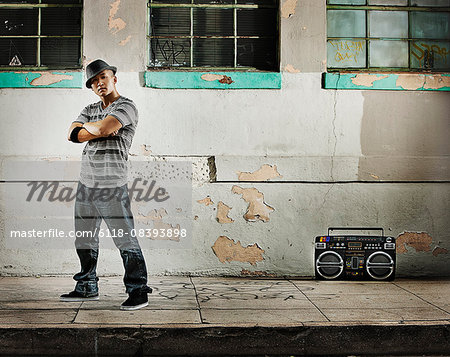 A young man, a breakdancer performer with a boombox on the street of a city.