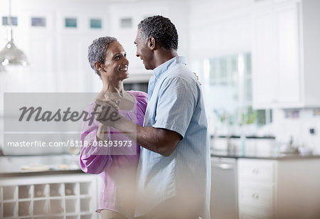 An affectionate mature African American couple, with their arms around each other dancing.