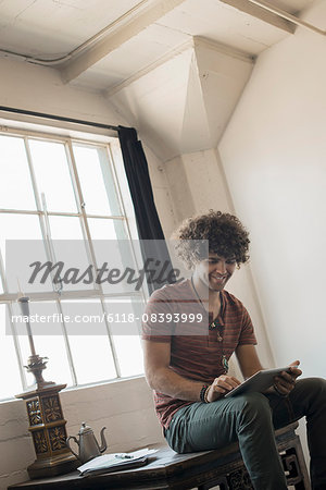 Loft living. A man sitting by a window using a digital tablet.