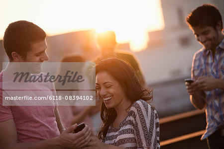 A group of men and women on a rooftop terrace having a party.