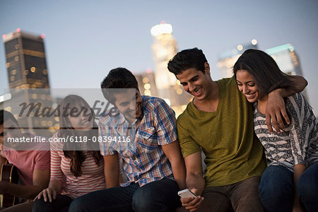 A small group of friends gathered on a rooftop terrace overlooking a city at twilight.