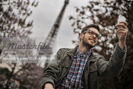 A man sitting on a park bench in the Champs de Mars under the Eiffel Tower.