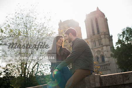 A couple in a romantic mood, side by side with arms around each other outside Notre Dame Cathedral in Paris.