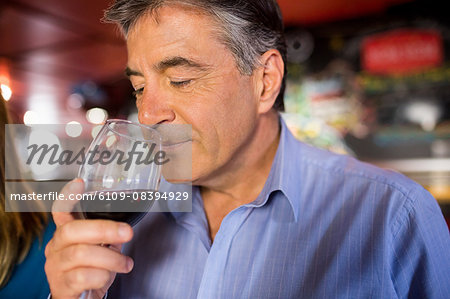 Man with grey hair drinking wine