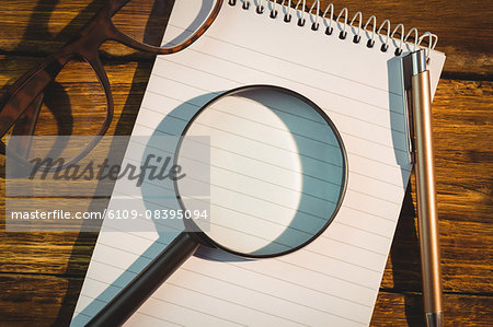 High angle view of magnifying glass with pen and notepad
