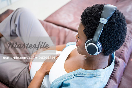 Happy pregnant woman using her headphones
