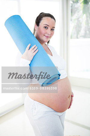 Pregnant woman holding her exercise mat