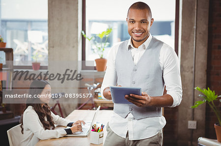 Portrait of smiling businessman holding digital tablet