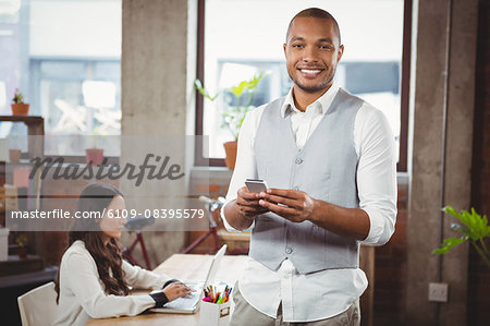 Portrait of smiling businessman holding phone