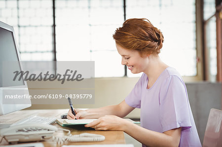 Happy businesswoman writing in book