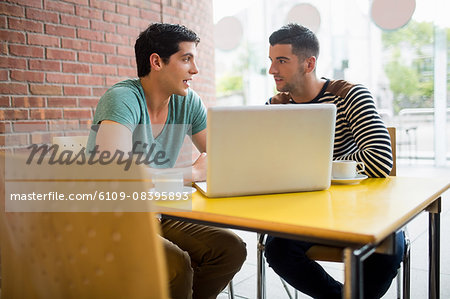 Students chatting in the cafe using laptop