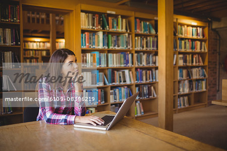 Thoughtful female student with laptopin library