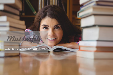 Happy female student leaning on book at table