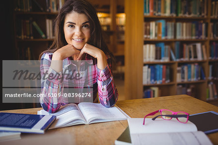 Confident female student with book at table