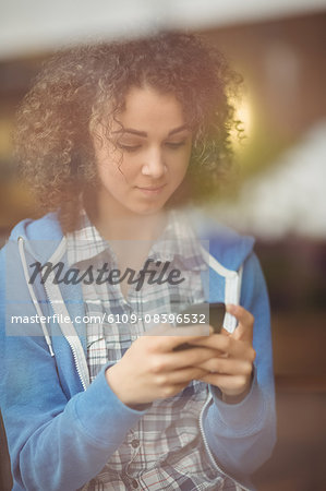 Pretty student using her phone in cafe