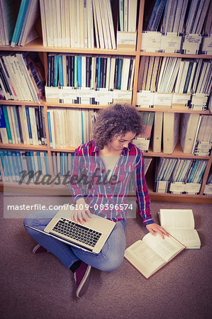 Pretty student in library using laptop