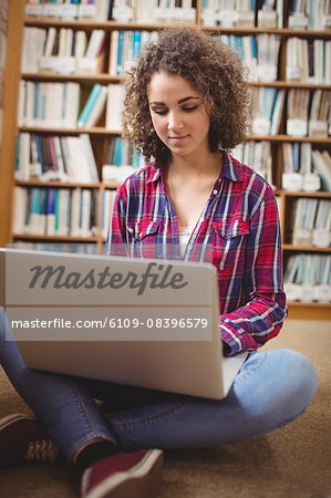 Pretty student in library using laptop