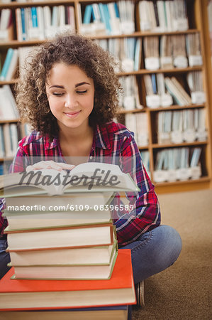 Pretty student in library with pile of books