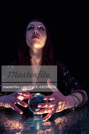 Fortune teller woman looking up and using crystal ball