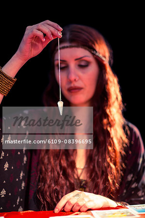 Fortune teller using pendulum with eyes closed