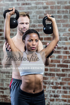 Woman lifting kettlebells with her trainer