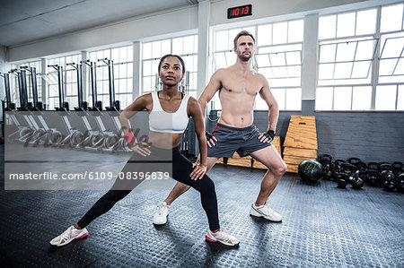 Muscular couple doing leg stretching