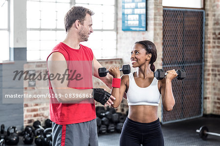 Smiling muscular couple lifting weight