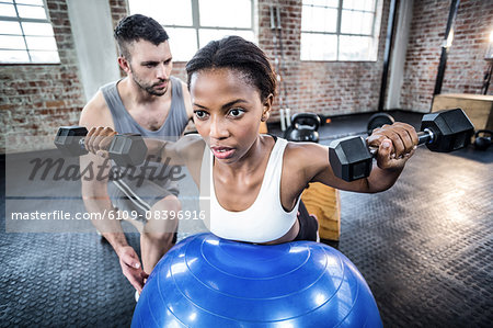 Personal trainer working with client holding dumbbell